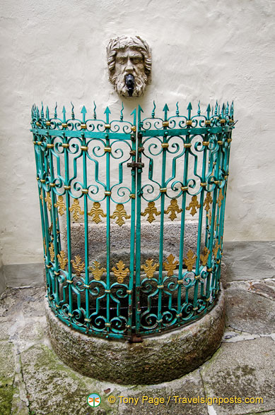 An ancient fountain with a colourful grill