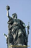 Germania holds the imperial crown in her raised right hand and the imperial sword in her left